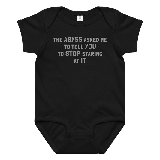 "The Abyss asked me to tell you to stop staring at it" printed on a black baby jersey bodysuit laying on a flat surface amongst other clothes