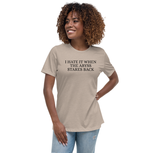 "I hate it when the abyss stares back" printed on a heather stone women's relaxed t-shirt worn by a female