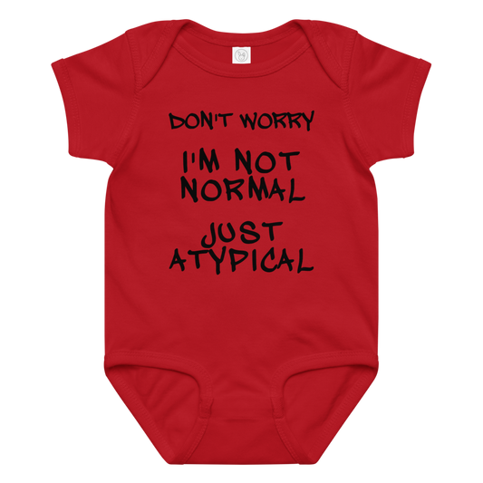 "Don't Worry I'm Not Normal Just Atypical" printed on a red baby jersey bodysuit laying on a flat surface amongst other clothes