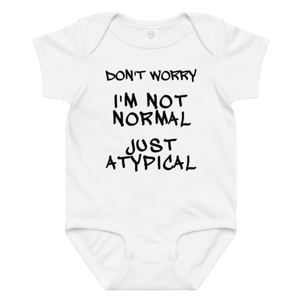 "Don't Worry I'm Not Normal Just Atypical" printed on a white baby jersey bodysuit laying on a flat surface amongst other clothes