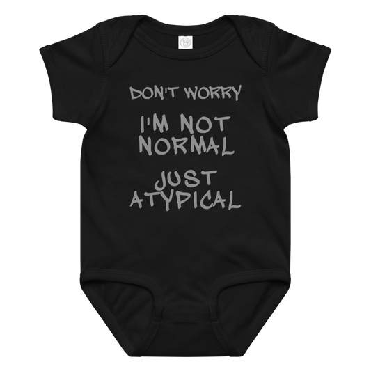 "Don't Worry I'm Not Normal Just Atypical" printed on a black baby jersey bodysuit laying on a flat surface amongst other clothes