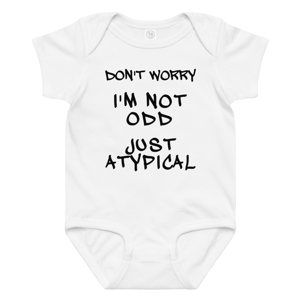 "Don't Worry I'm Not Odd Just Atypical" printed on a white baby jersey bodysuit laying on a flat surface amongst other clothes