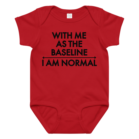 "With me as the baseline, I am normal" printed on a red baby jersey bodysuit laying on a flat surface amongst other clothes