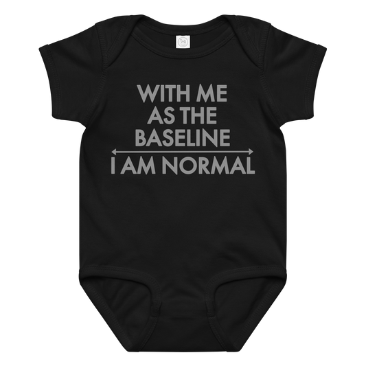 "With me as the baseline, I am normal" printed on a black baby jersey bodysuit laying on a flat surface amongst other clothes