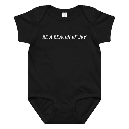 "Be a beacon of joy" printed on a black baby jersey bodysuit laying on a flat surface amongst other clothes