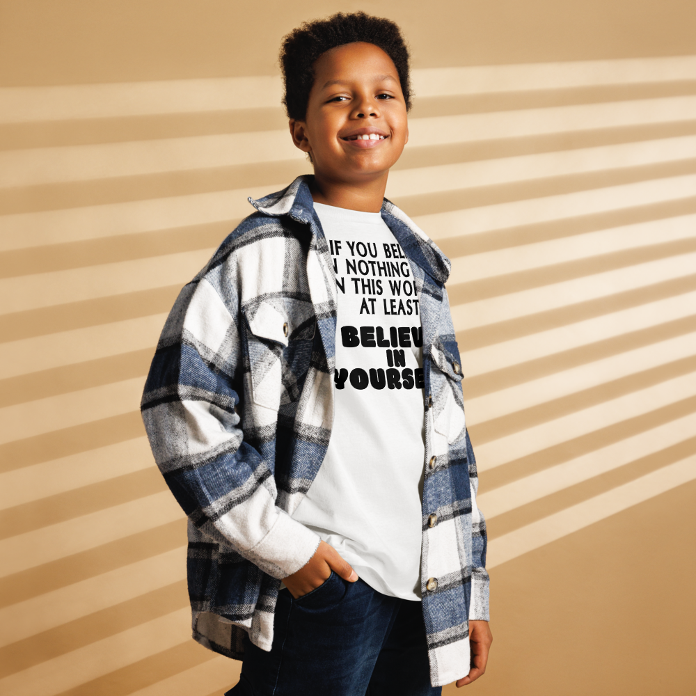 "If you believe in nothing else in this world, at least believe in yourself" printed on a white youth classic tee worn by a male also wearing a jacket