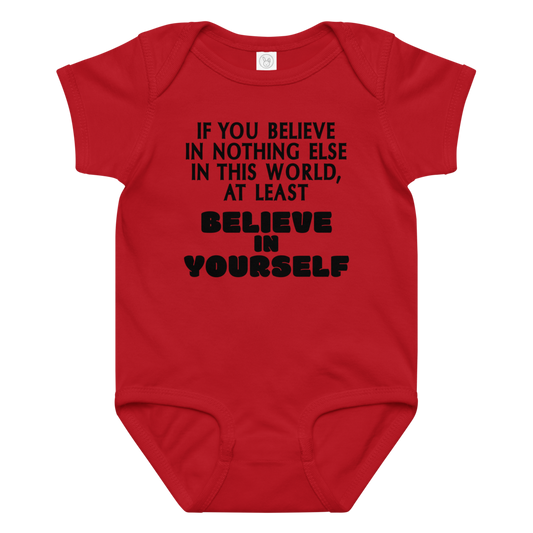 "If you believe in nothing else in this world, at least believe in yourself" printed on a red baby jersey bodysuit laying on a flat surface amongst other clothes