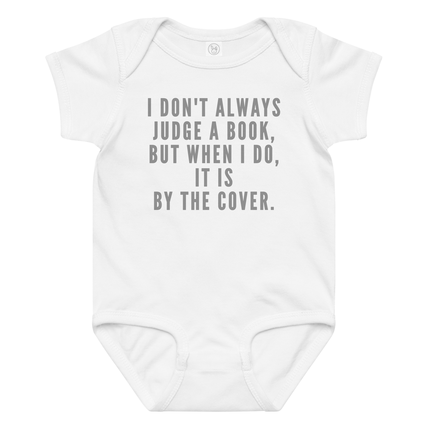 "I Don't always Judge a Book, but when I do, it's by the cover." printed on a white baby jersey bodysuit laying on a flat surface amongst other clothes