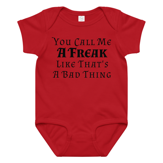 "You Call Me A Freak Like That's A Bad Thing" printed on a red baby jersey bodysuit laying on a flat surface amongst other clothes