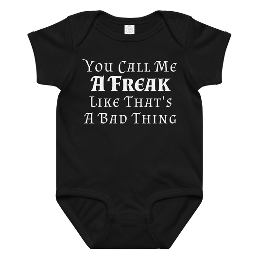"You Call Me A Freak Like That's A Bad Thing" printed on a black baby jersey bodysuit laying on a flat surface amongst other clothes