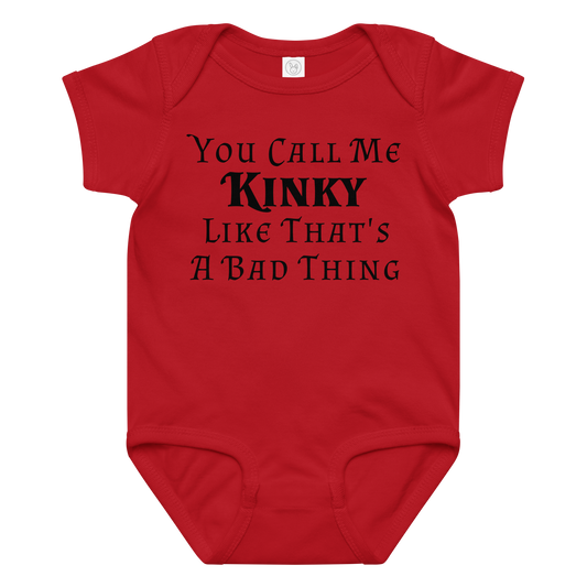 "You Call Me Kinky Like That's A Bad Thing" printed on a red baby jersey bodysuit laying on a flat surface amongst other clothes