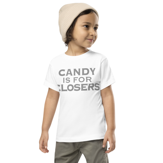 "Candy Is For Closers" printed on a white toddler short sleeve tee worn by a male wearing a cap