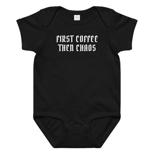 "First Coffee Then Chaos" printed on a black baby jersey bodysuit laying on a flat surface amongst other clothes