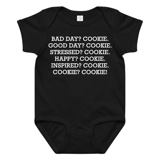 "Bad Day? Cook. Good Day? Cook. Stressed? Cook. Happy? Cook. Inspired? Cook. Cook? Cook!" printed on a black baby jersey bodysuit laying on a flat surface amongst other clothes