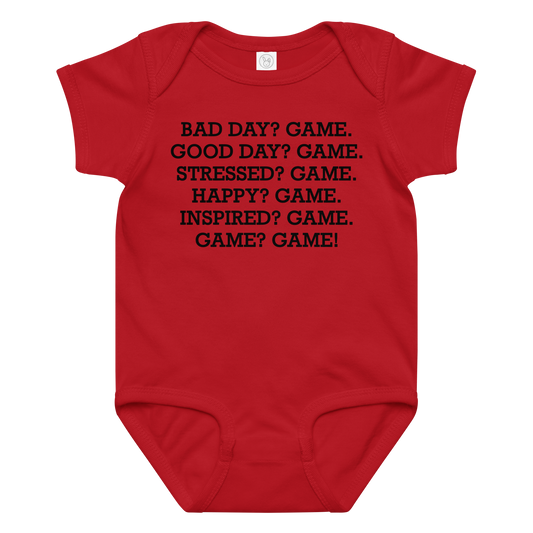"Bad Day? Game. Good Day? Game. Stressed? Game. Happy? Game. Inspired? Game. Game? Game!" printed on a red baby jersey bodysuit laying on a flat surface amongst other clothes