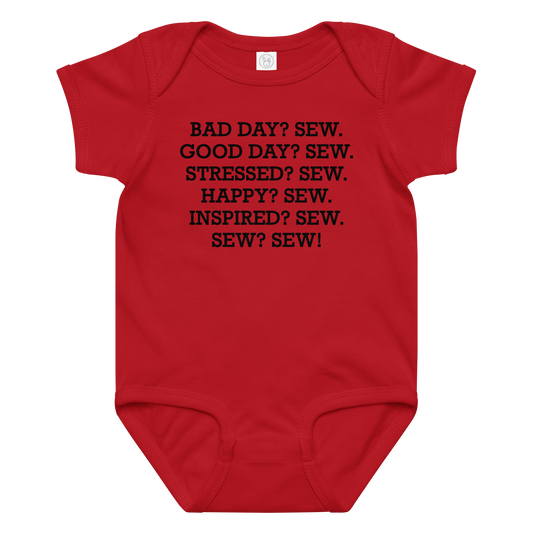 "Bad Day? Sew. Good Day? Sew. Stressed? Sew. Happy? Sew. Inspired? Sew. Sew? Sew!" printed on a red baby jersey bodysuit laying on a flat surface amongst other clothes