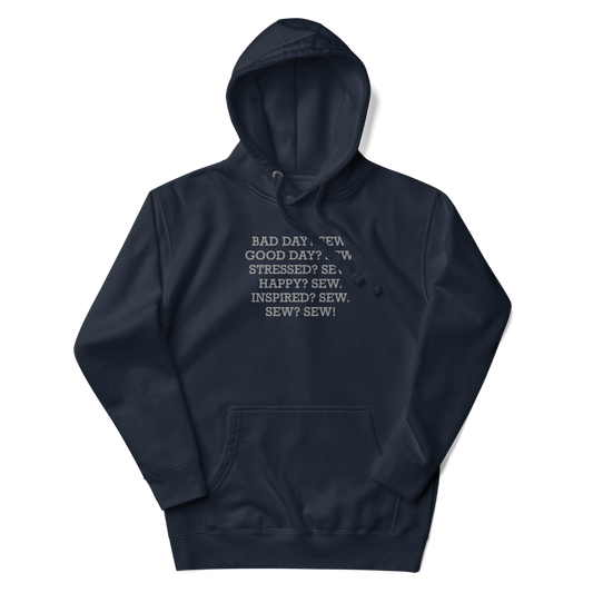 "Bad Day? Sew. Good Day? Sew. Stressed? Sew. Happy? Sew. Inspired? Sew. Sew? Sew!" printed on a navy blazer unisex hoodie laying on a flat surface with the hood up