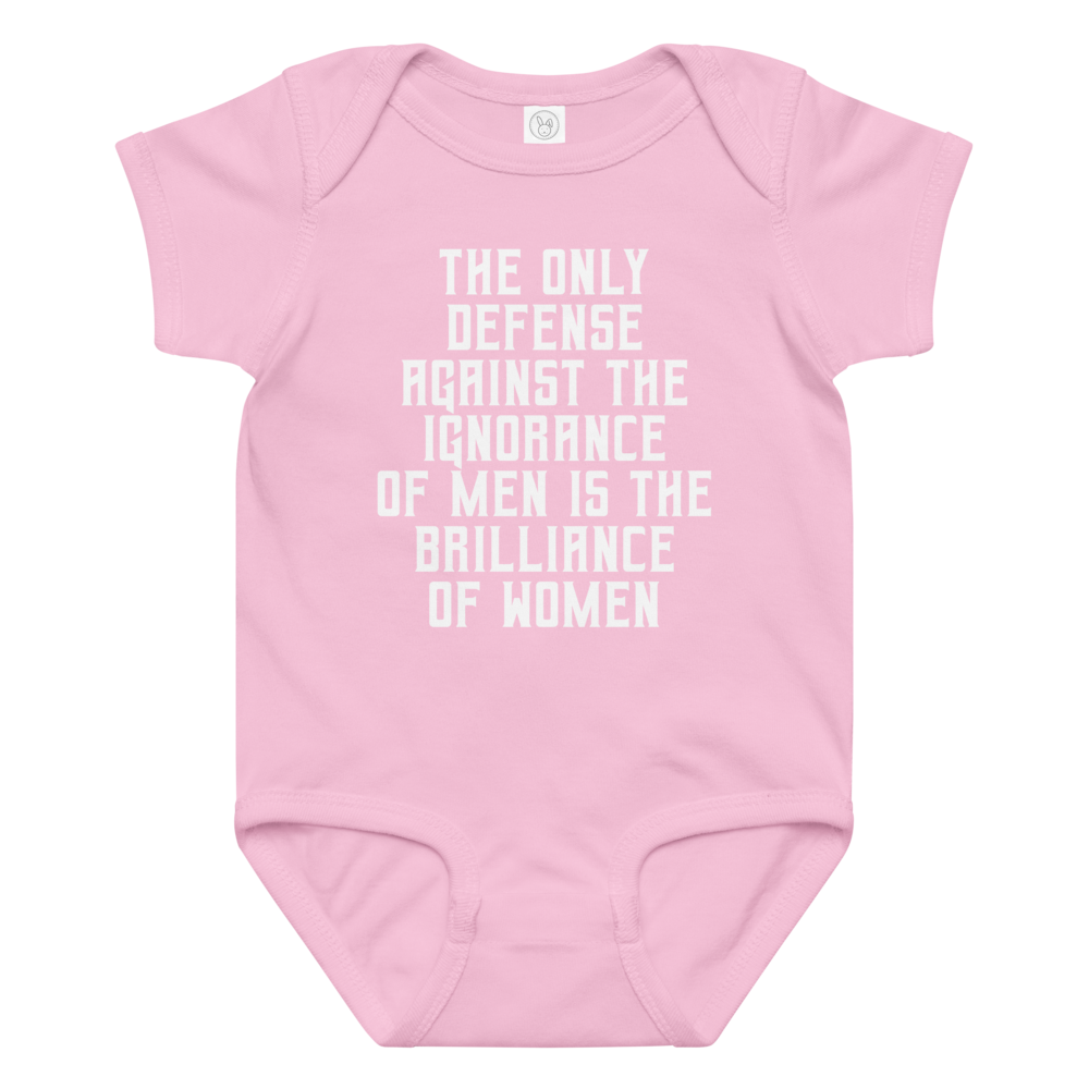 "The Only defense against the ignorance of men is the brilliance of women" printed on a pink baby jersey bodysuit laying on a flat surface amongst other clothes