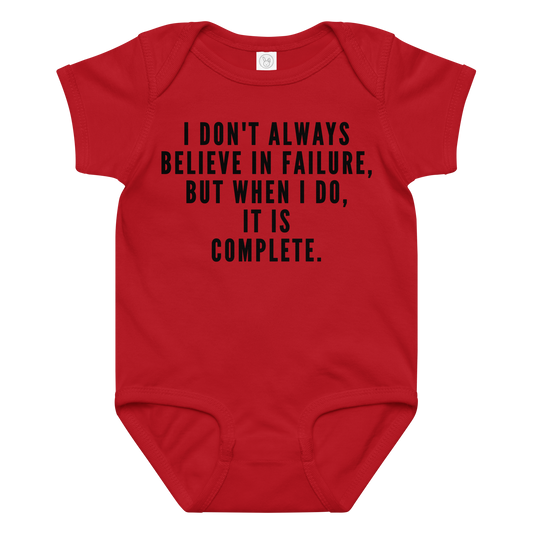 "I don't always believe in failure, but when I do, it is complete." printed on a red baby jersey bodysuit laying on a flat surface amongst other clothes
