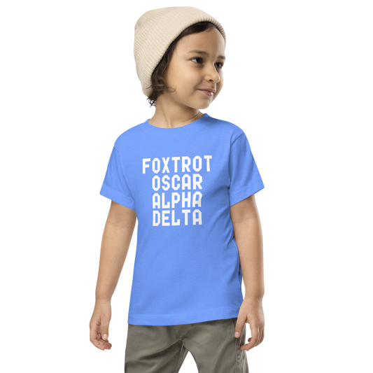 "Foxtrot Oscar Alpha Delta" printed on a heather columbia blue toddler short sleeve tee worn by a male wearing a cap