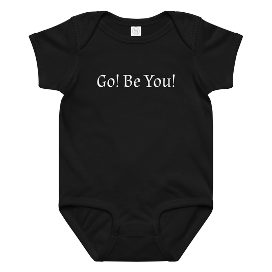 "Go! Be You!" printed on a black baby jersey bodysuit laying on a flat surface amongst other clothes
