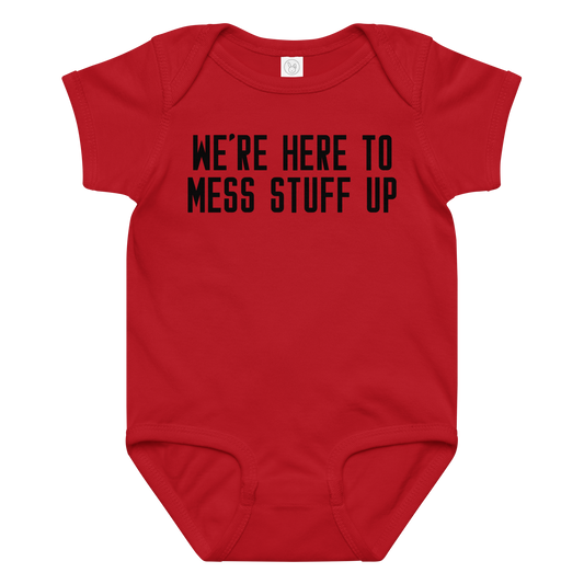 "We're Here To Mess Stuff Up" printed on a red baby jersey bodysuit laying on a flat surface amongst other clothes