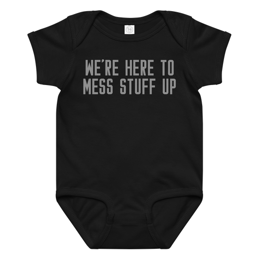 "We're Here To Mess Stuff Up" printed on a black baby jersey bodysuit laying on a flat surface amongst other clothes