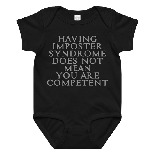 "Having Imposter Syndrome does not mean you are competent" printed on a black baby jersey bodysuit laying on a flat surface amongst other clothes