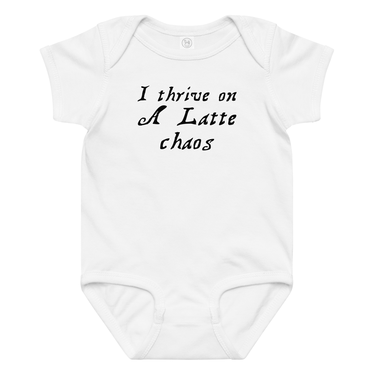 "I thrive on a latte chaos" printed on a white baby jersey bodysuit laying on a flat surface amongst other clothes