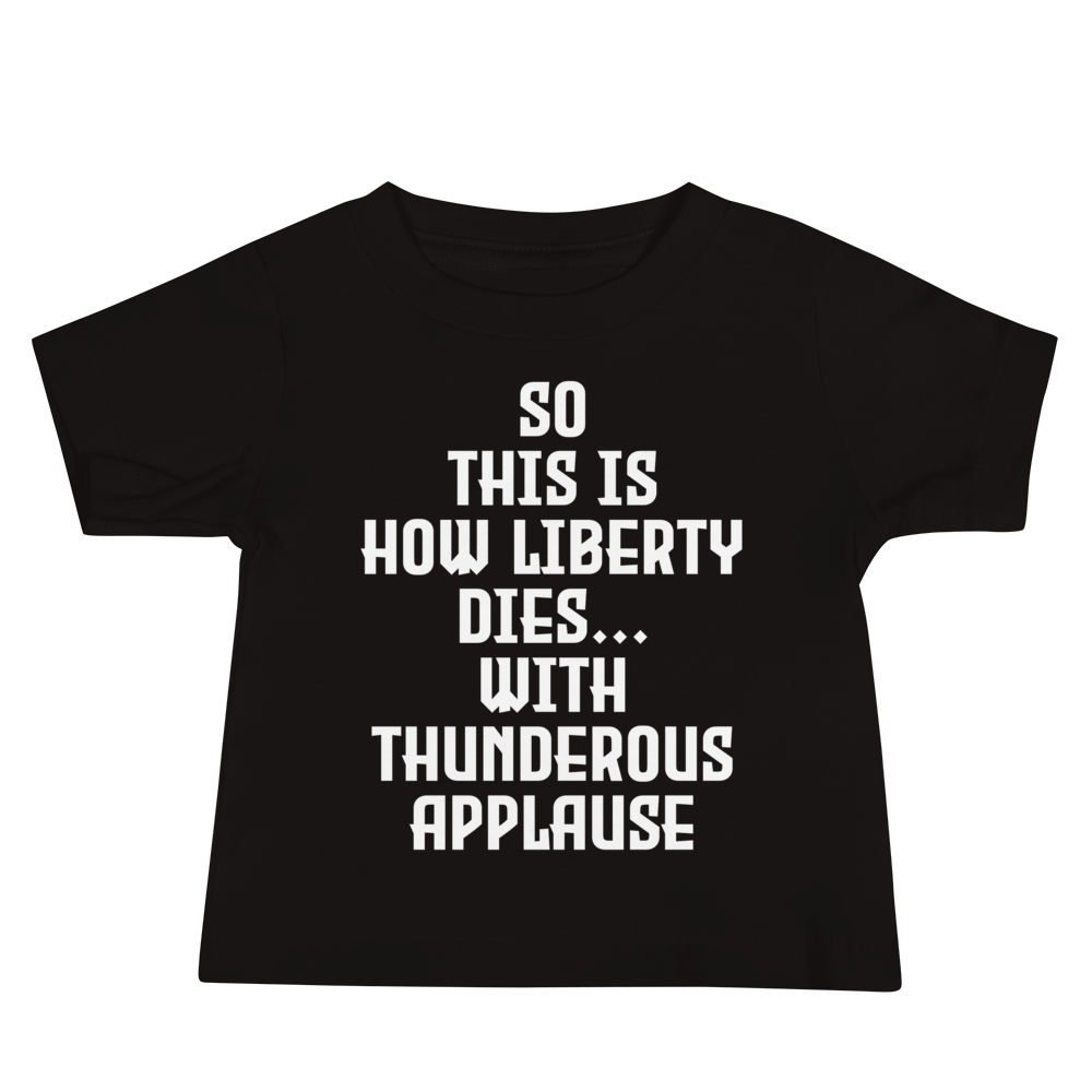 "So this is how liberty dies… with thunderous applause" printed on a black baby jersey short sleeve tee laying on a flat surface