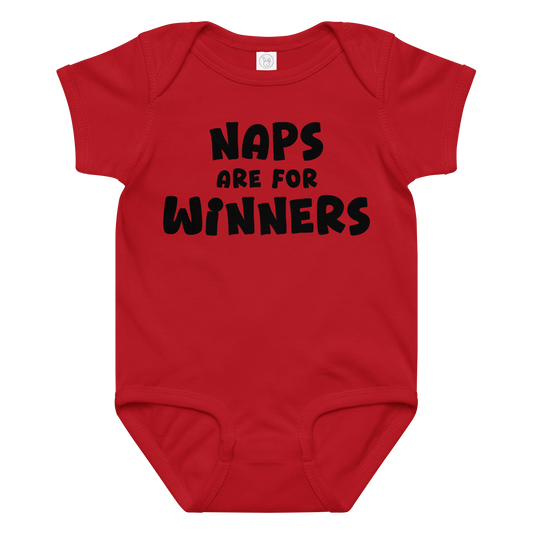 "Naps Are For Winners" printed on a red baby jersey bodysuit laying on a flat surface amongst other clothes