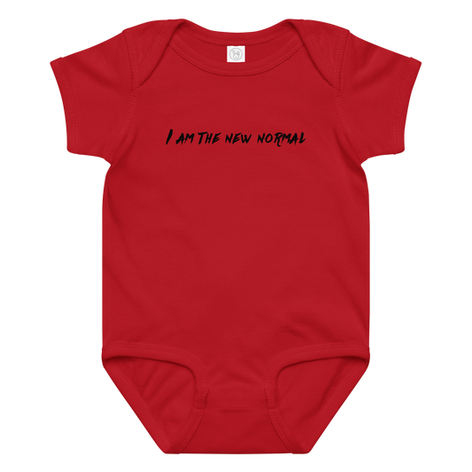 "I am the new normal" printed on a red baby jersey bodysuit laying on a flat surface amongst other clothes
