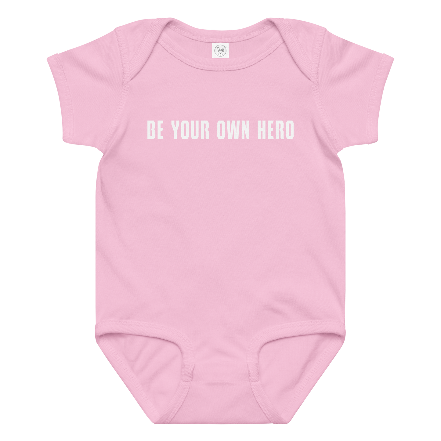 "Be your own here" printed on a pink baby jersey bodysuit laying on a flat surface amongst other clothes