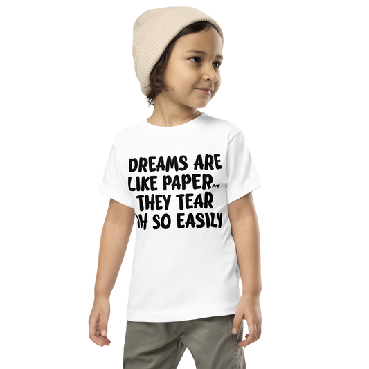 "Dreams are like paper, they tear oh so easily" printed on a white toddler short sleeve tee worn by a male wearing a cap