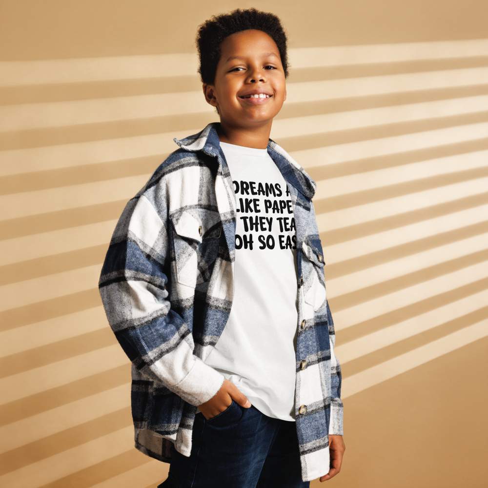 "Dreams are like paper, they tear oh so easily" printed on a white youth classic tee worn by a male also wearing a jacket