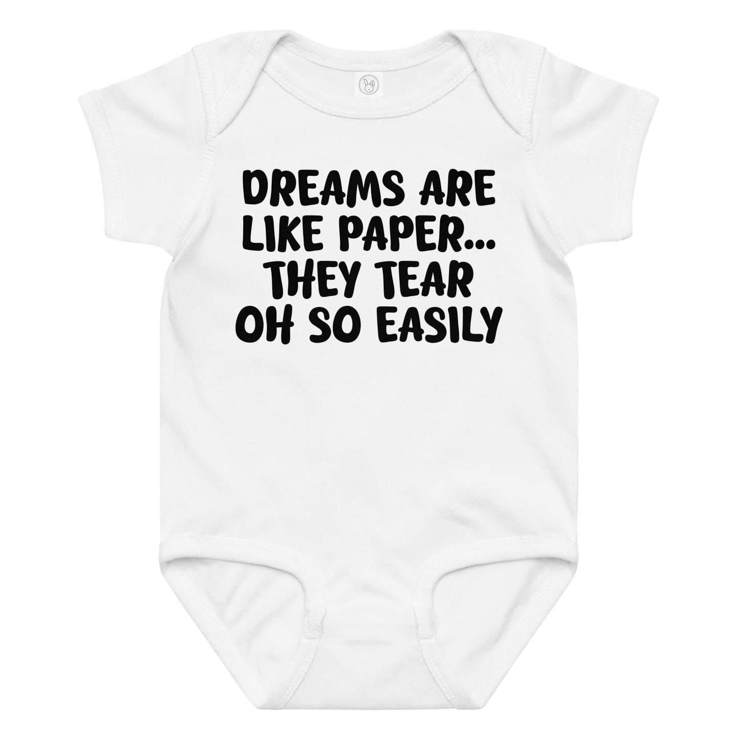 "Dreams are like paper, they tear oh so easily" printed on a white baby jersey bodysuit laying on a flat surface amongst other clothes