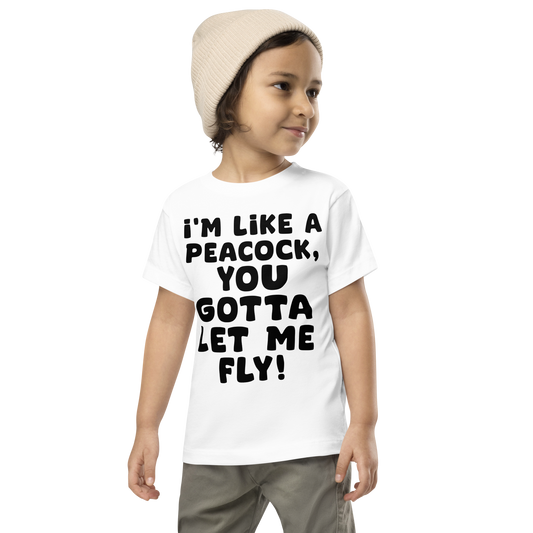 "I'm like a peacock, you gotta let me fly!" printed on a white toddler short sleeve tee worn by a male wearing a cap