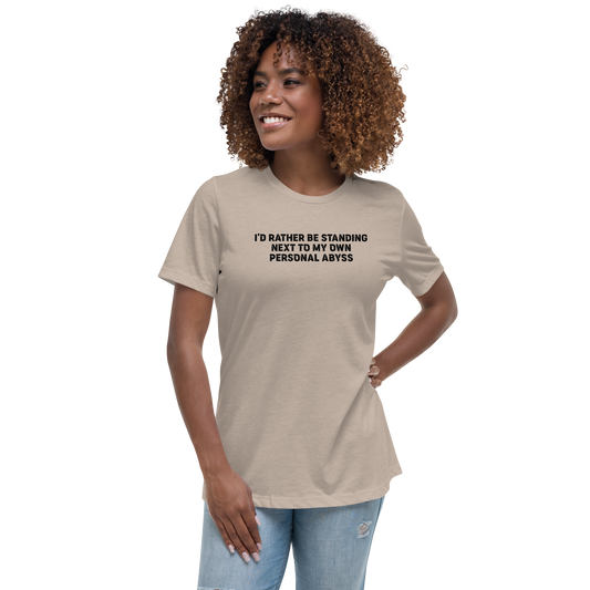 "I'd rather be standing next to my own personal abyss" printed on a heather stone women's relaxed t-shirt worn by a female