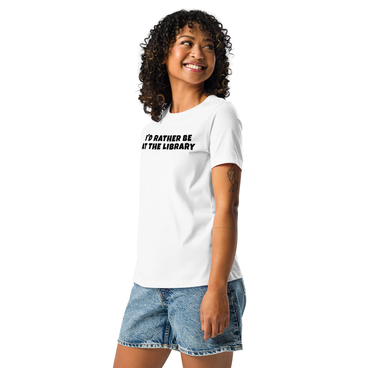 "I’d rather be at the library" printed on a white women's relaxed t-shirt worn by a female