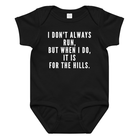"I don't always run, but when I do, it is for the hills." printed on a black baby jersey bodysuit laying on a flat surface amongst other clothes
