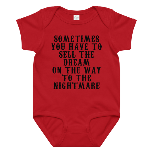 "Sometimes you have to sell the dream on the way to the nightmare" printed on a red baby jersey bodysuit laying on a flat surface amongst other clothes