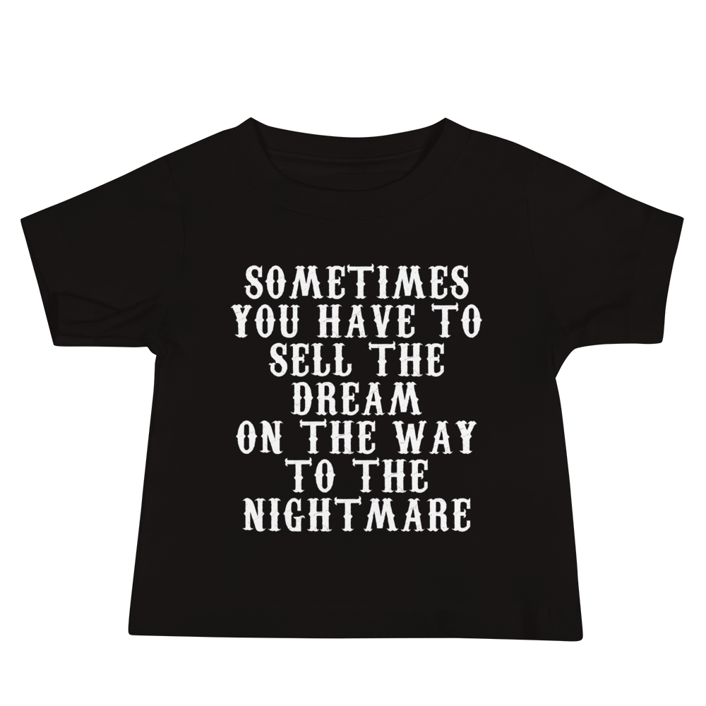 "Sometimes you have to sell the dream on the way to the nightmare" printed on a black baby jersey short sleeve tee laying on a flat surface