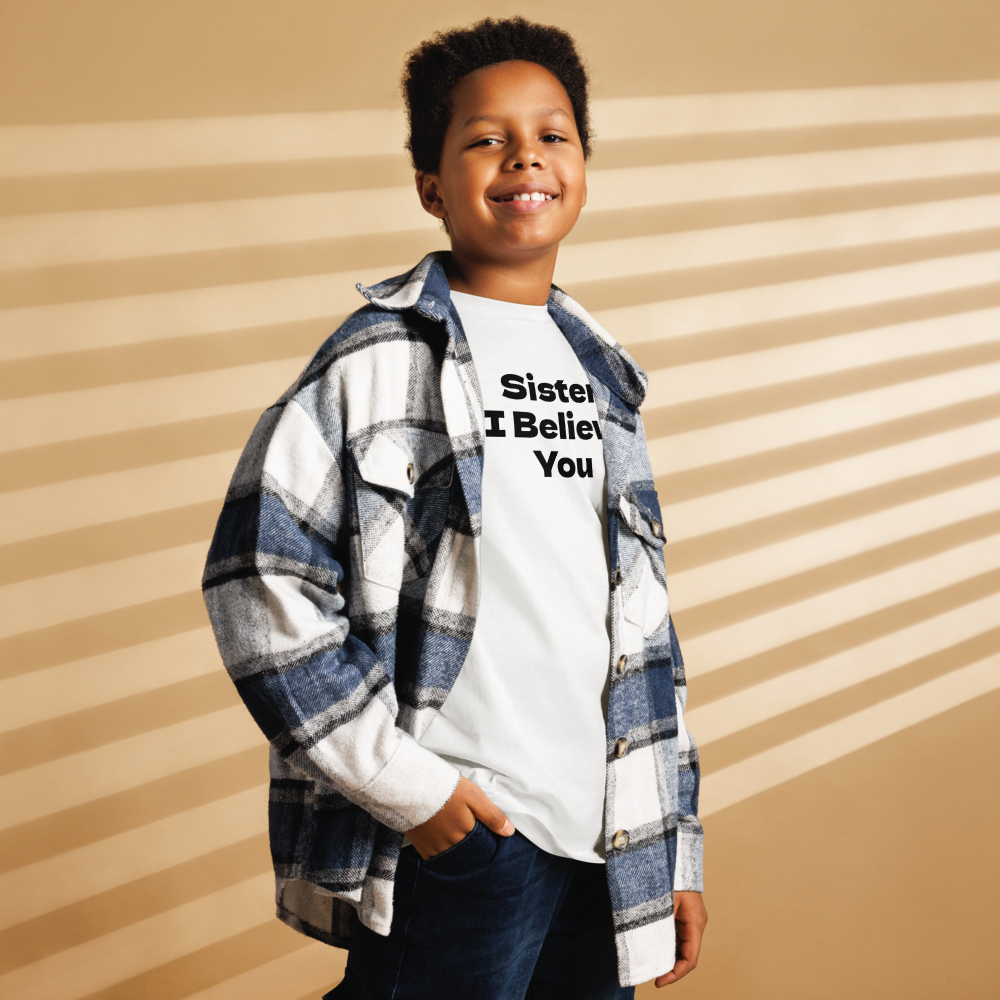 "Sister, I Believe You!" printed on a white youth classic tee worn by a male also wearing a jacket