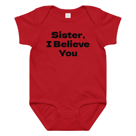 "Sister, I Believe You!" printed on a red baby jersey bodysuit laying on a flat surface amongst other clothes