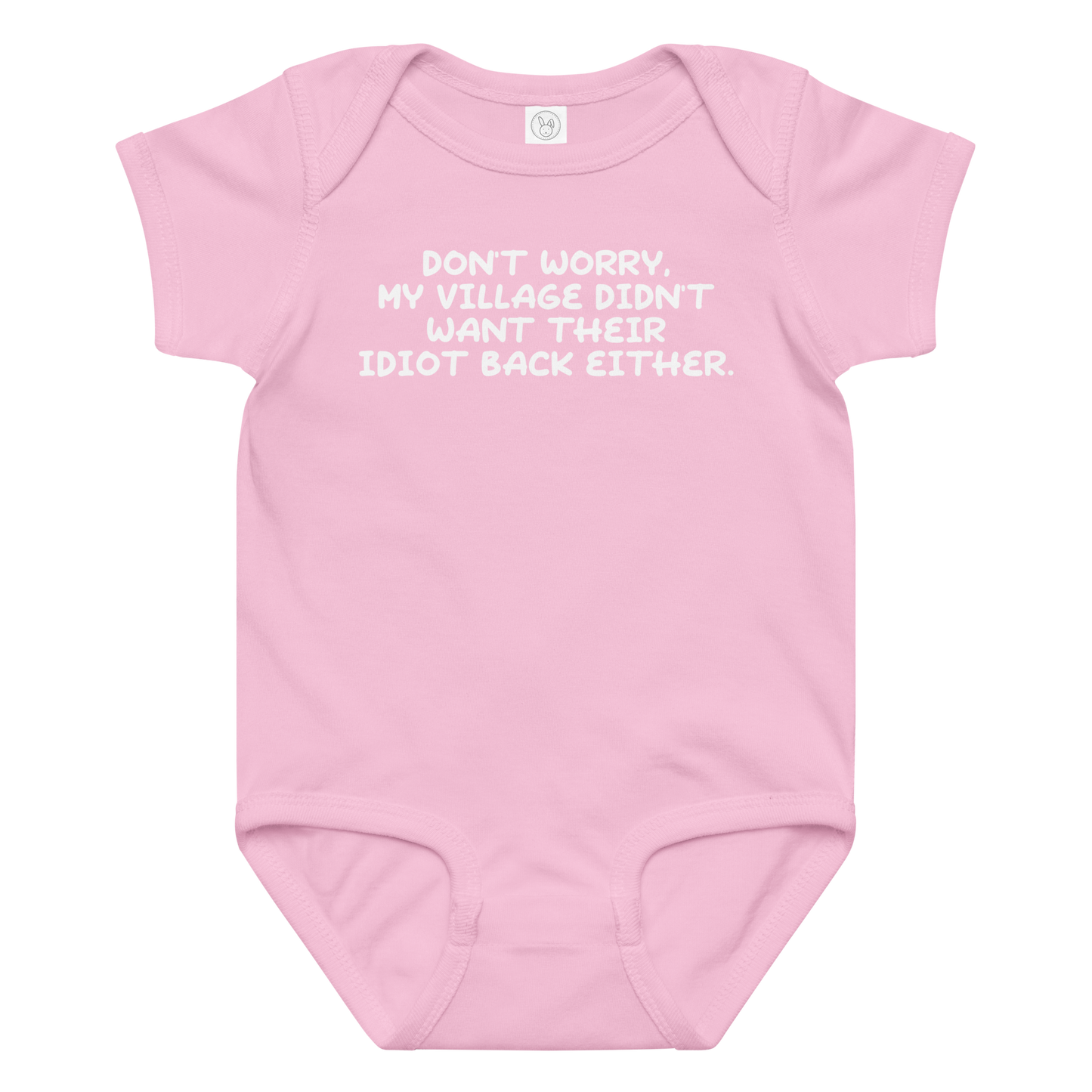 "Don't worry, my village didn’t want their idiot back either." printed on a pink baby jersey bodysuit laying on a flat surface amongst other clothes