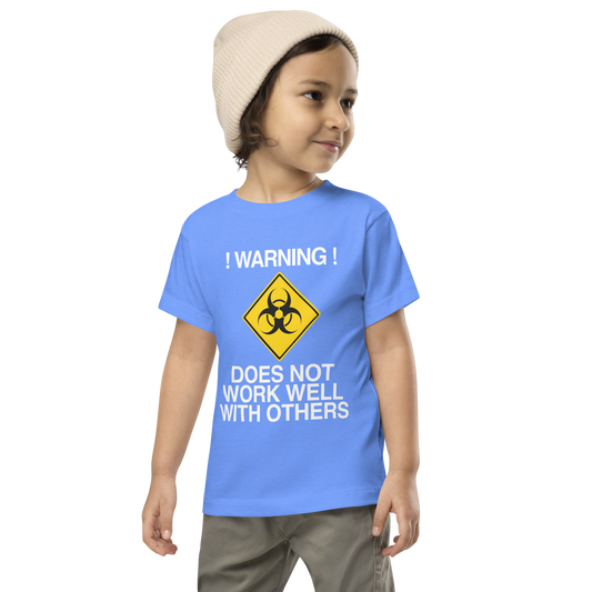 "!Warning! Does Not Work Well With Others" printed on a heather columbia blue toddler short sleeve tee worn by a male wearing a cap