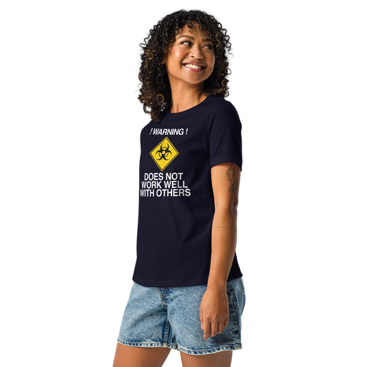 "!Warning! Does Not Work Well With Others" printed on a navy women's relaxed t-shirt worn by a female