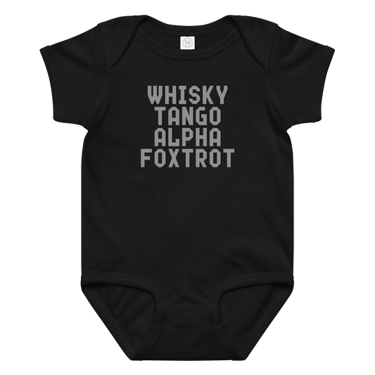 "Whisky Tango Alpha Foxtrot" printed on a black baby jersey bodysuit laying on a flat surface amongst other clothes