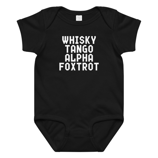 "Whisky Tango Alpha Foxtrot" printed on a black baby jersey bodysuit laying on a flat surface amongst other clothes