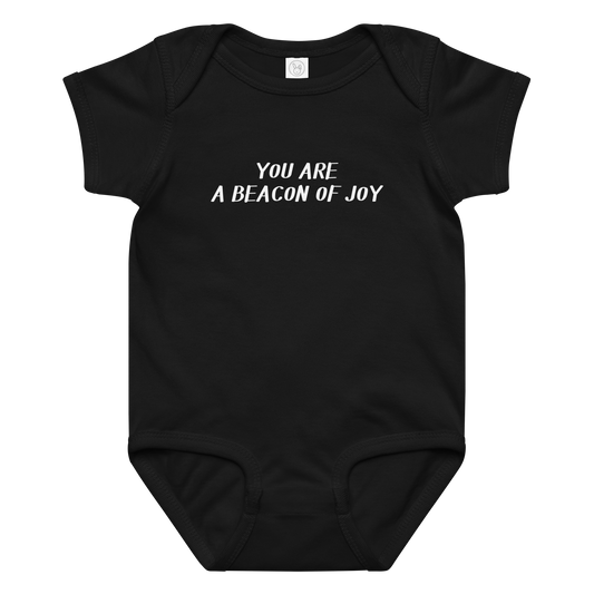 "You are a beacon of joy" printed on a black baby jersey bodysuit laying on a flat surface amongst other clothes